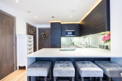 a kitchen with a white counter and stools at Chelsea Harbour Living in London
