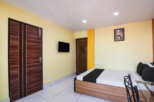 1 dormitorio con 1 cama y TV en la pared en OYO Royal Crown Banquet, en Calcuta