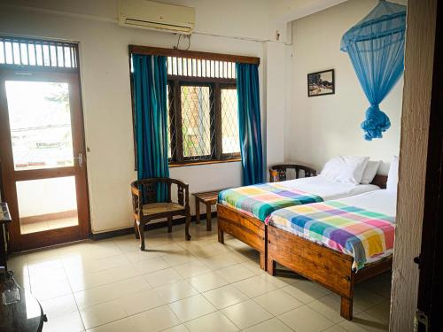 a bedroom with a bed and two chairs and a window at Sharon Inn in Kandy