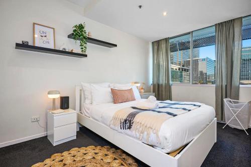 a white bedroom with a large bed and a window at Collins Street City Stay - 2 Min to Southern Cross in Melbourne