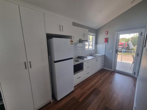 a kitchen with white cabinets and a white refrigerator at Gulgong Tourist Park in Gulgong