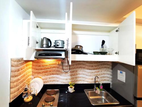 a kitchen with white cabinets and a sink at Modern 1BR with balcony and 100mbps wifi in Manila