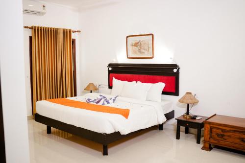a bedroom with a large bed with a red headboard at Marari Beach Palace in Mararikulam