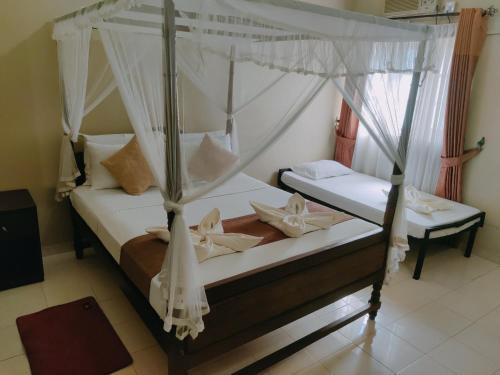 a bedroom with two beds with mosquito nets at Grand Colonial Viveka in Kurunegala