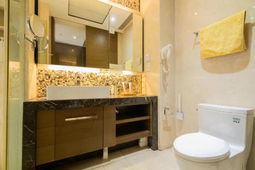 a bathroom with a toilet and a sink and a mirror at 邻致公寓东站中汇店 in Guangzhou