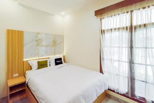 a bedroom with a white bed and a window at Urbanview Hotel Tritia Lampung in Kedaton