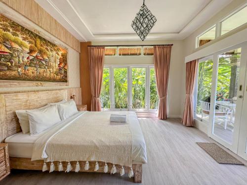 a bedroom with a large bed and a large window at villa senyum in Canggu