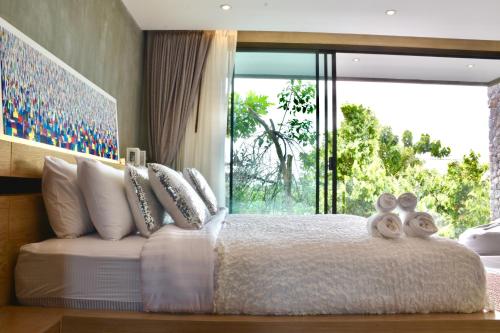 ein Schlafzimmer mit einem großen Bett mit einem großen Fenster in der Unterkunft Villa Papaya @ Kamala Beach in Kamala Beach