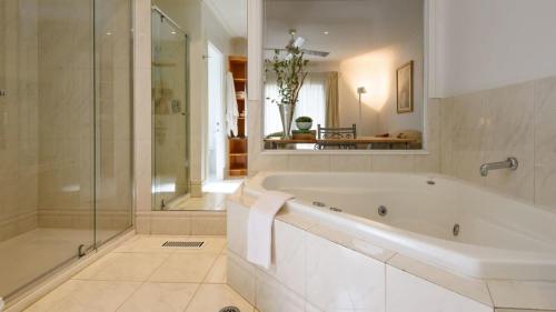a white bathroom with a tub and a shower at Lakeside Suite 2 - Lake View & Spa Bath in Daylesford