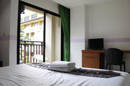 a bedroom with a bed and a balcony with a television at Diamond Crown in Patong Beach
