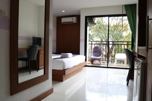 a bedroom with a bed and a desk and a balcony at Diamond Crown in Patong Beach