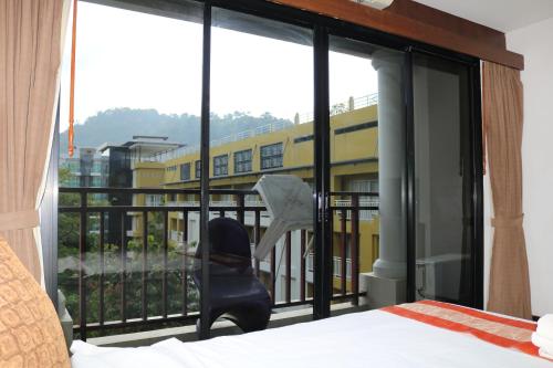 a bedroom with a window with a chair on a balcony at Diamond Crown in Patong Beach