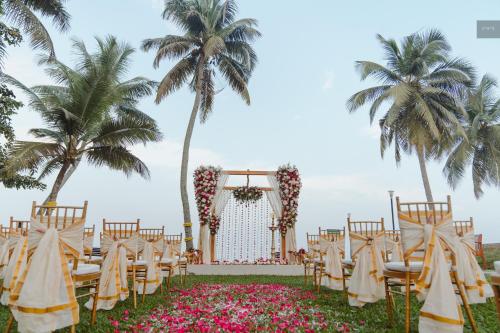 a wedding aisle with chairs and palm trees at Backwater Ripples Kumarakom in Kumarakom