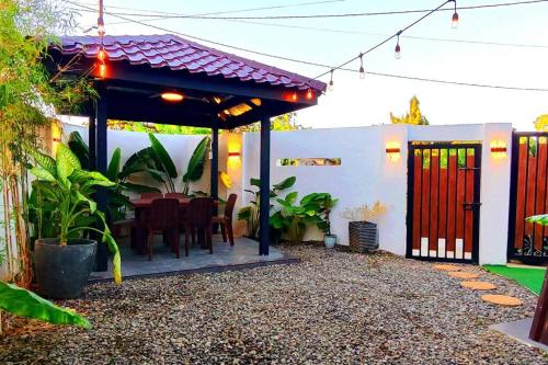 eine Terrasse mit einem Esstisch unter einer Pergola in der Unterkunft M Villa Staycation in Los Baños