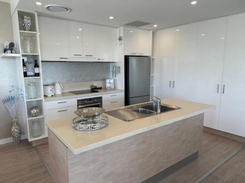 a kitchen with white cabinets and a counter top at Grand Mercure Allegra Hervey Bay in Hervey Bay