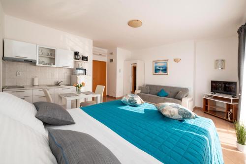 a bedroom with a large blue bed and a kitchen at Apartmani Trogir in Trogir