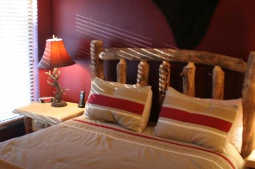 a bed with a wooden headboard and a table with a lamp at Brianwood Ski-In Condo Steps from Giant Steps Lift in Brian Head