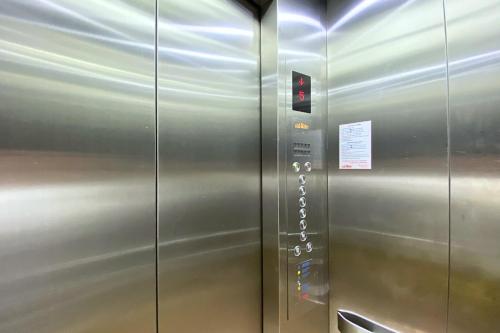 a metal elevator with a red light on it at Grand Sansook Omnoi in Ban Khlong Om Noi