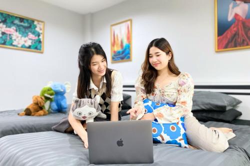 two girls sitting on a bed with a laptop at Grand Sansook Omnoi in Ban Khlong Om Noi