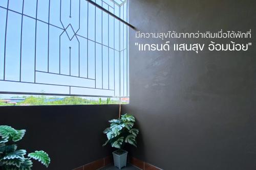 a plant sitting next to a window with a drawing on the wall at Grand Sansook Omnoi in Ban Khlong Om Noi