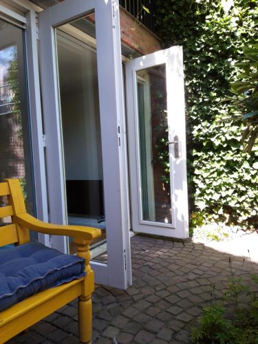 アイントホーフェンにあるSint Lambertusstraatの黄色のベンチ付きのパティオへ続くオープンドア