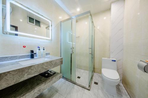 a bathroom with a toilet and a glass shower at Mando Hotel - Kunming Changshui International Airport in Kunming