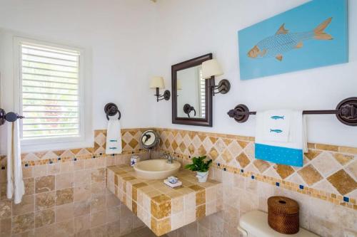 ein Badezimmer mit einem Waschbecken und einem Fischbild an der Wand in der Unterkunft 4 BR Villa on Seventh Hole in La Romana