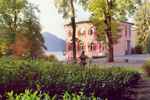 una casa rosa con árboles y una boca de incendios en Hotel Monte Verità en Ascona