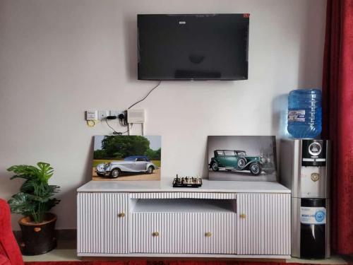 um centro de entretenimento branco com uma televisão de ecrã plano na parede em macdade apartment em Nairobi