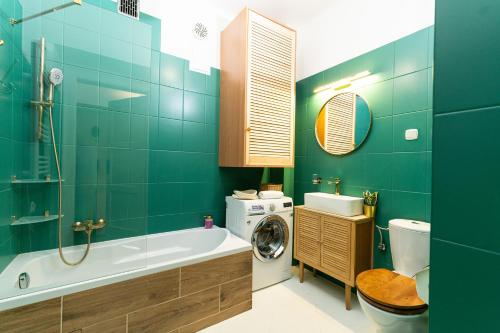 a bathroom with a tub and a washing machine at Cozy Old Town Studio in Krakow