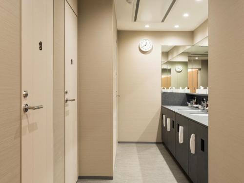 a bathroom with two sinks and a clock on the wall at Glansit Kyoto Kawaramachi in Kyoto