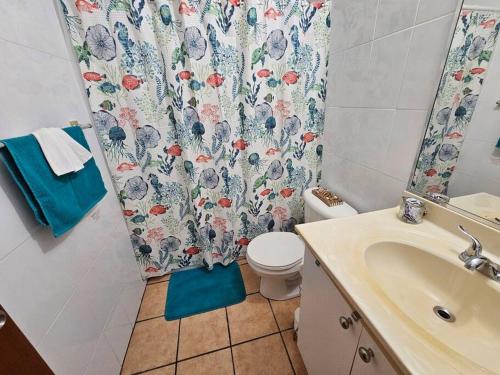 y baño con aseo y cortina de ducha. en Kodesh Vacation Club Combate, Cabo Rojo, en El Combate
