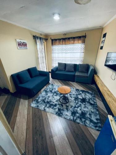 ein Wohnzimmer mit blauen Sofas und einem Tisch in der Unterkunft Cozy House, Quiet Area Kimandolu in Arusha