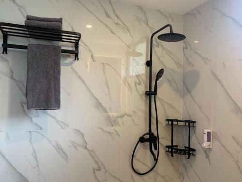 a shower in a bathroom with white marble at Urbanview Hotel Nardis Living near UMY in Ngabean