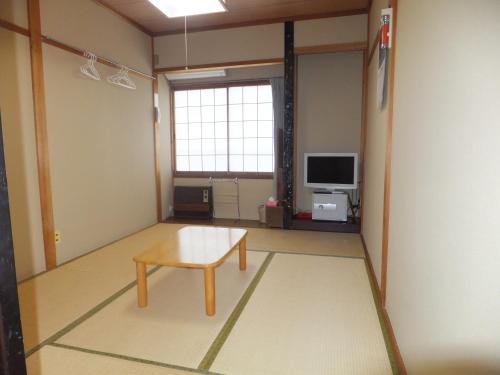 a living room with a table and a tv at Minshuku Iwatakan in Takayama