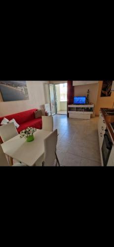 een woonkamer met een witte tafel en een rode bank bij Appartamento estivo in Vieste