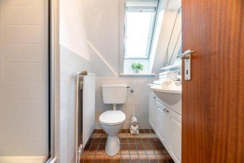 een badkamer met een toilet, een wastafel en een raam bij widj-loft in Oldsum