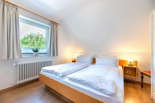 een slaapkamer met een bed met witte lakens en een raam bij widj-loft in Oldsum