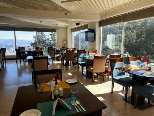 a restaurant with tables and chairs and large windows at Royal Tulip Luxury Hotel, Kufri, Shimla in Shimla