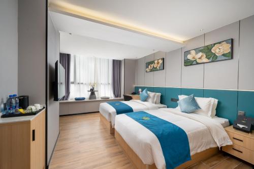 two beds in a room with blue and white at Vizhanwan Hotel Shenzhen International Convention and Exhibition Center in Shenzhen