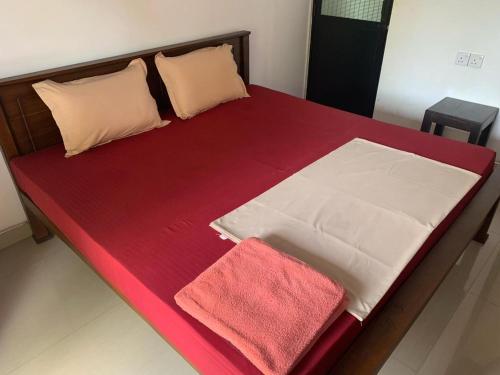 a bed with red sheets and two towels on it at Serendip Villa Holiday HomeTalalla Sri Lanka in Matara