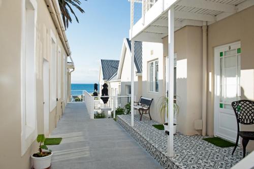 a walkway between two buildings with the ocean in the background at Boulders Beach Hotel, Cafe and Curio shop in Simonʼs Town