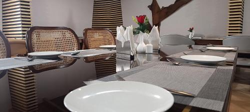 uma sala de jantar com uma mesa com pratos brancos e cadeiras em HOTEL GRP INN CITY HOME em Pithorāgarh