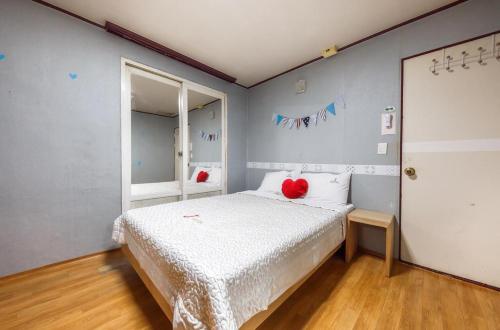 J Motel في يوسو: غرفة نوم عليها سرير ومخدة حمراء