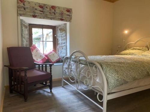 a bedroom with a bed and a chair and a window at The Barn Yr Ysgubor in Llandysul