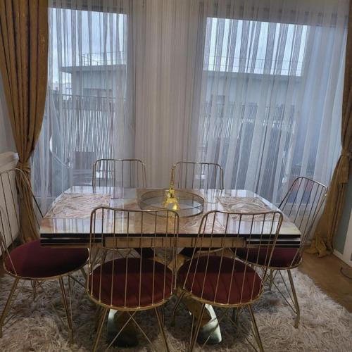 une table à manger avec quatre chaises et une table en verre avec un vase dans l'établissement Appartement proche de Paris nord -Stade de France -Adidas Arena- Montmartre, à Deuil-la-Barre
