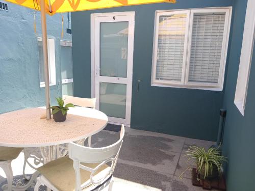 eine Terrasse mit einem Tisch, Stühlen und einem Sonnenschirm in der Unterkunft Boulders Beach Hotel, Cafe and Curio shop in Simonʼs Town