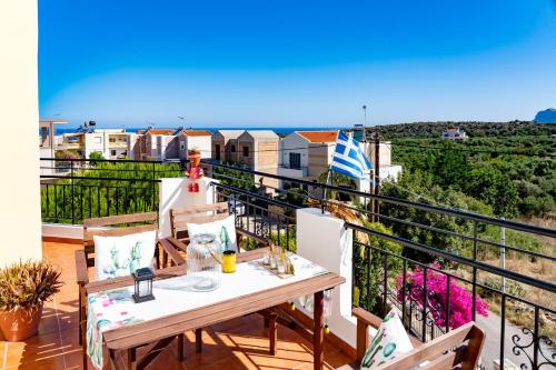 a balcony with a table and chairs and the ocean at Robellini Palm in Kounoupidhianá