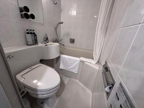 a white bathroom with a toilet and a sink at Hotel Keihan Tenmabashi in Osaka