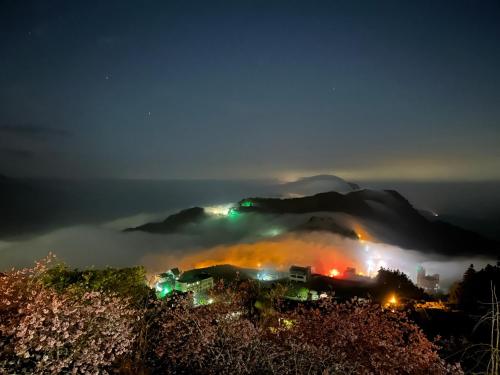 a foggy mountain at night with lights on a city at Siangting B&B in Fenchihu
